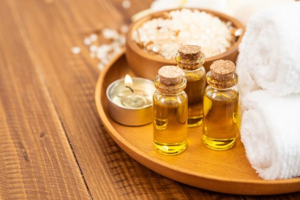 Free photo sea salt, towels, aroma oil in bottles and flowers on vintage wooden background.